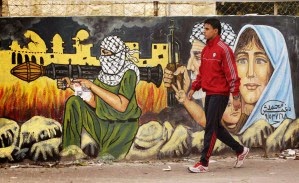 Palestinien passant devant mur porteur d'une reprsentation guerrire