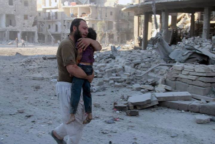 photo d'un pre palestinien, au milieu de ruines, portant enfant victime