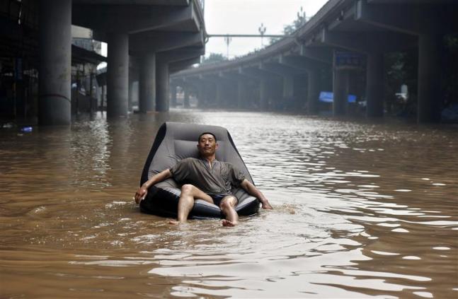 illustration du changement climatique, la Mer envahit les cités... photo de citoyen se promenant sur les eaux avec fauteuil gonflable entre infrastructures