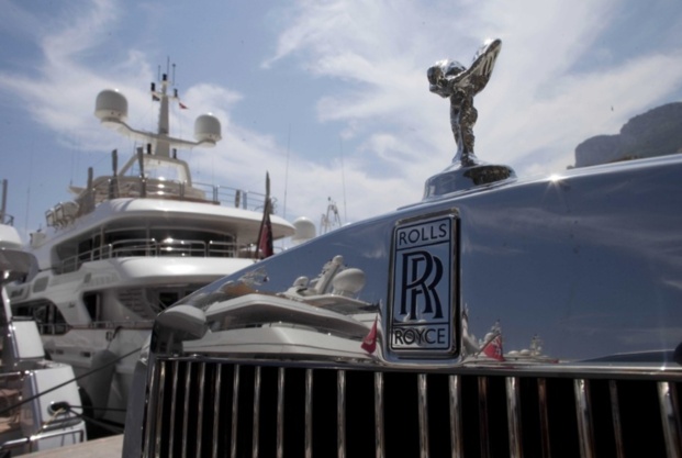 évocation des riches qui suscitent l'austérité pour leurs profits... photo d'un capot d'auto Rolls Royce devant yatchs.