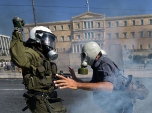 évocation des conséquences de l'austérité exigée en Grèce par la Troïka... photo duel, policier, manifestant, masque à gaz, édifice public en fond