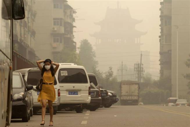exemple de pollution atmosphérique en Chine photo de jeune femme attachant son masque dans la rue enfumée