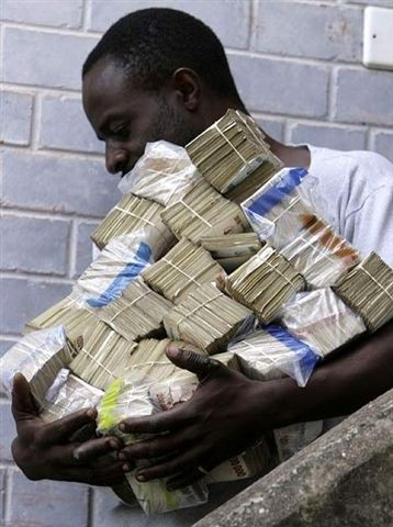 exemple de dévaluation de la monnaie, ici au Zimbabwe photo d'un homme transportant un tas de liasses de billets au Zimbabwe
