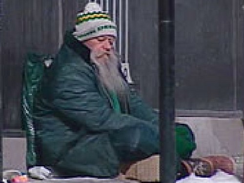 Il est par terre...et pourtant il rêve...il nous rappelle qu’il est un homme parce qu’il rêve... photo floutée d'un SDF, assis, derrière poteau.