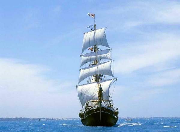 Mon navire, l’aile du départ... photo d'un voilier, vu de face dans le bleu au large d'une côte.
