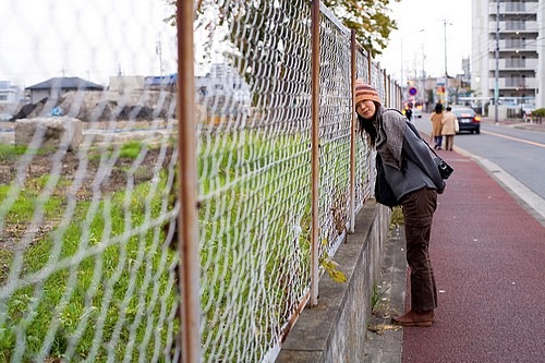 jeune femme, tte appuye sur grillage dans une rue au Japon